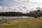 a gorgeous winter landscape at Rhodes Jordan park with a blue lake, yellow winter grass lush green trees, people walking