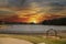 a gorgeous winter landscape at Rhodes Jordan park with a blue lake, yellow winter grass lush green trees, people walking