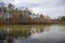 a gorgeous winter landscape at Rhodes Jordan park with a silky green lake, bare winter trees, lush green trees with blue sky