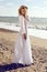 Gorgeous woman with blond curly hair in elegant beach dress