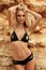 Gorgeous woman with blond hair in elegant swimsuit posing on beach