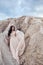 Gorgeous woman brunette in the mountains at sunset and blue sky with clouds. The woman looks into the distance in a long white