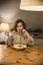 Gorgeous woman eating a plate of Tagliatelle al Ragu Bolognese in a cozy dining room