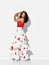 Gorgeous woman hispanic dancer wearing red white gown with flower print dances Carmen flamenco holding hands at head