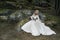 A gorgeous woman, a mythical creature, a queen, she is in a white dress, on large stones, in the autumn forest The concept of a fa