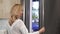 Gorgeous woman smiling to the camera opening the fridge at the kitchen