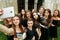 Gorgeous women group in black dresses taking selfie having fun and laughing in the city. stylish lady party with gothic theme.