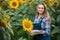 Gorgeous, young, adorable, energetic, female farmer cultivating from one of the sunflowers from the green field