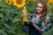 Gorgeous, young, adorable, energetic, female farmer holding a bottle of sunflower oil in the middle of a beautiful sunflower field