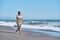 gorgeous young African American woman strolling along the beach in a summery skirt