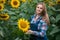 Gorgeous, young, energetic, female farmer cultivating from one of the sunflowers from the big green field