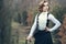 Gorgeous young woman with elegant Victorian hairstyle walking in the misty autumn park