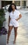 Gorgeous young woman poses in city wearing white romper