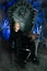 Gothic woman with bird on huge scary throne with blue spooky light ready for Halloween party