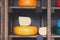 Gouda cheese as wheel and piece on wooden shelf of a grocery sho