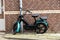 Gouda, South Holland/The Netherlands - February 15 2020: Black and green moped left behind in the city center of Gouda with a lock