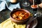 Goulash or stew in copper pan with spoon on rustic kitchen table. Eintopf, chili con carne. Traditional hungarian dish. Homemade