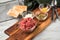 Gourmet beefsteak Tatar with lean raw beef filet, capers, egg yolk, onions, toast bread on wooden board and light marble