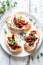 Gourmet Bruschetta With Roasted Tomatoes and Fresh Basil on a White Plate