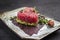 Gourmet fish tartar raw from tuna fillet with hashed avocado, umebashi and Japanese spice on modern design plate