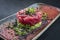 Gourmet fish tartar raw from tuna fillet with hashed avocado, wasabi and Japanese spice on modern design plate