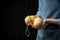 Gourmet italian cheese scamorza in hands of cheese maker in blue apron on black background