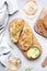 Gourmet lunch with avocado salmon toasts on rye bread and rose wine glasses, gray table background, top view