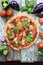 Gourmet rustic pizza with aubergines, tomatoes and basil on shabby blue background