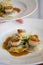 Gourmet scallops and ravioli with sauce on a white