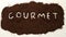 Gourmet Spelled Out in Ground Coffee on White Background. Gourmet Coffee.