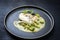 Gourmet style fried skrei cod fish filet with caviar, avocado slices and mustard mango creme on a modern Nordic design plate