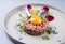 Gourmet tartar raw from beef fillet with yellow of the egg and vegetable on modern design dish