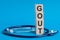 Gout word written on wooden blocks and stethoscope on light blue background