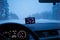 A GPS screen inside car and view of winter road outside.