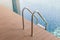 Grab bars ladder entrance to clear blue swimming pool.