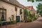 Graceful alleyway with brick houses, shrubs and flowered pots on a cloudy day at Gouda.