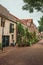 Graceful alleyway with brick houses, shrubs and flowered pots on a cloudy day at Gouda.