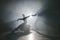 Graceful ballerina and her male partner dancing elements of classical or modern ballet in dark with floodlight backlight