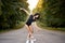 Graceful ballet dancer or classic ballerina dancing on road in forest.