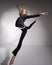 Graceful barefoot ballerina in a business suit jumping with a glass of coffee in her hands on a white background.