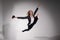 Graceful barefoot ballerina in a business suit jumping with a glass of coffee in her hands on a white background.