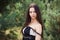 Graceful charming brunette model posing in black dress in coniferous park