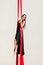 Graceful female aerialist performing dance on red hanging silks