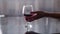 Graceful female hand takes a glass of red wine from the table, light background