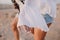 Graceful girl in vintage blouse and denim shorts with trendy white manicure having fun outside running on the sand