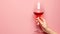 Graceful hand holding red wine glass on pastel background with ample space for text placement