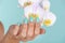 Graceful Hand with Turquoise Manicure and Delicate Lilac Orchid Flower