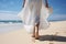 A graceful lady in long white skirt walk on sand beach.