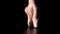 Graceful legs of a ballerina in white pointe shoes. Ballerina shows classic ballet pas. Shot in a darkness on spotlights