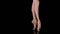 Graceful legs of a ballerina in white pointe shoes. Ballerina shows classic ballet pas. Shot in a darkness on spotlights